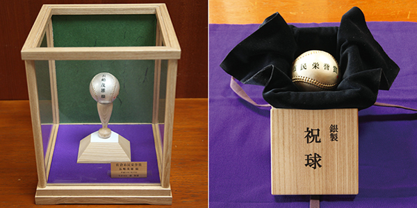 (左）バットの上に銀製の野球ボールがのっている作品がケースに入っている写真（右）国民栄誉賞と書かれたボールが木箱に入っている写真