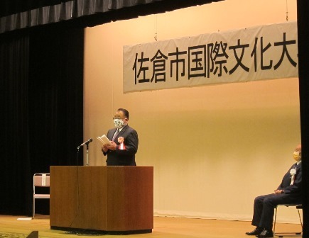 佐倉市国際文化大学開講式にて、胸章リボンを付けた市長が演台に立ち、挨拶をしている写真