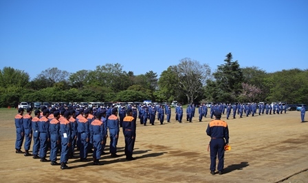 青空の下、活動服を着た消防団員が並んでいる写真