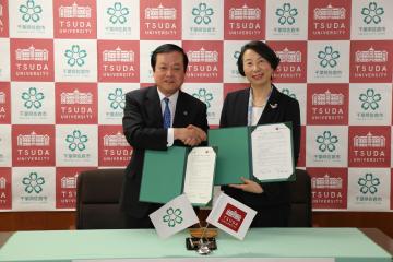 蕨佐倉市長と津田塾大学 高橋学長がそれぞれ協定書を手に持ち握手を交わしている写真