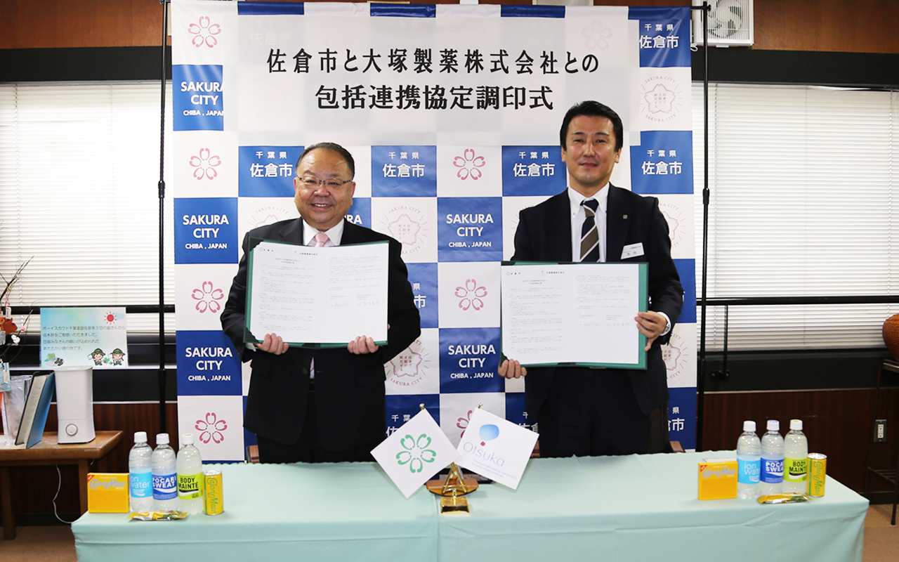 調印式にて西田市長と大塚製薬株式会社の池内支店がそれぞれ協定書を手に持ち笑顔で写っている写真