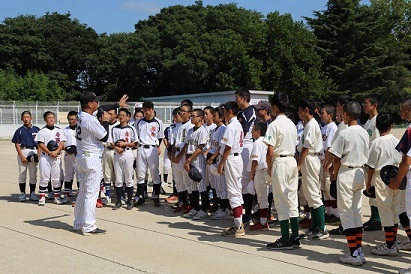 各チームのユニフォームを着た子供たちの前でマイクを持ち説明をしている武藤コーチの写真