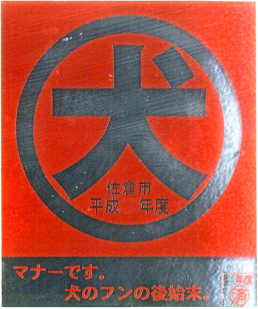 銀色円の中に「犬」と書かれている赤地の門標の写真