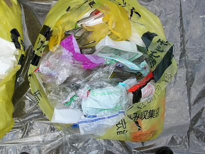 ビニール袋やプラスチック容器が入った黄色いごみ袋の写真