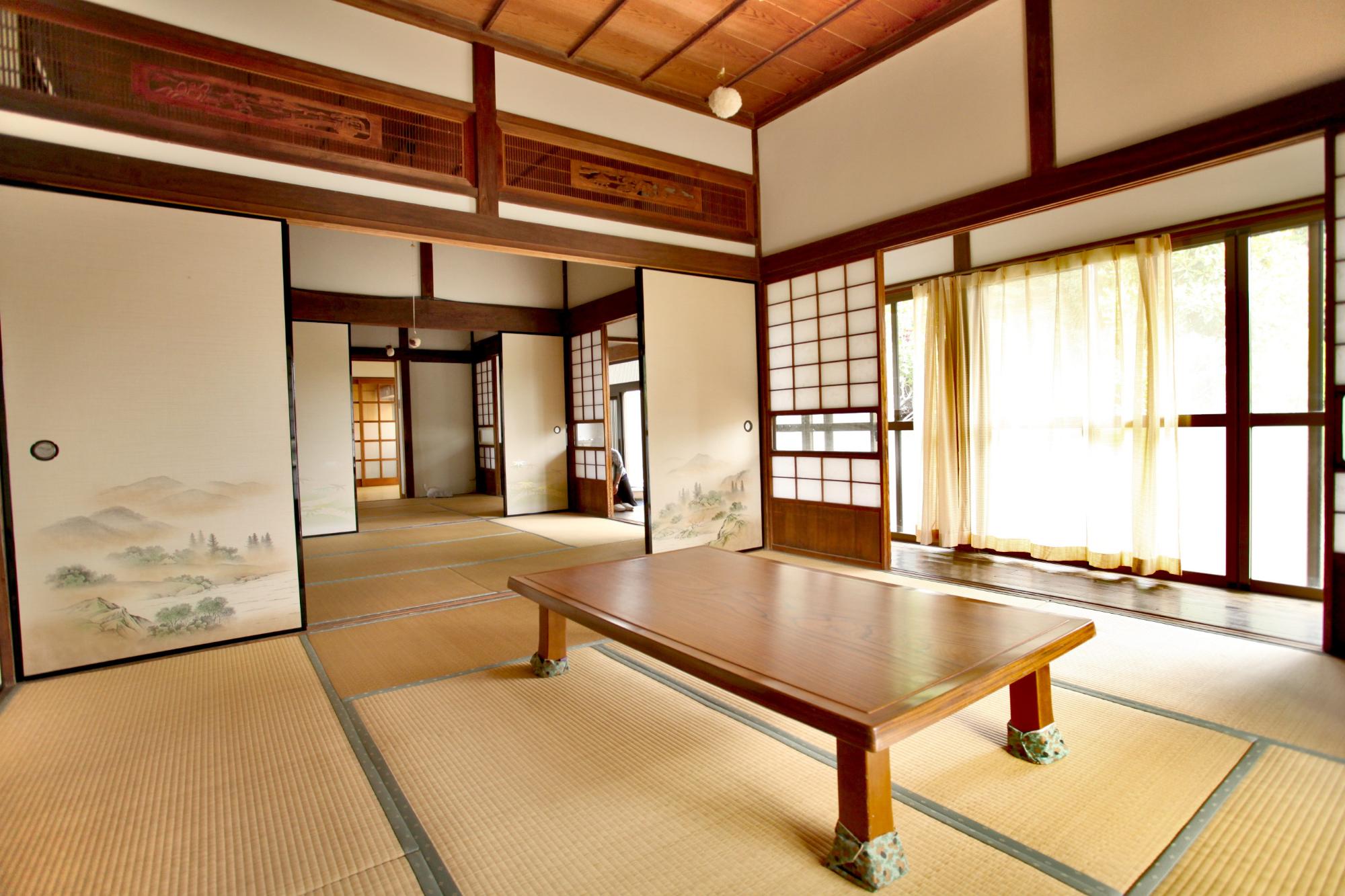 奥に部屋が続く、障子や畳のある和室の手前の部屋にテーブルが置かれている写真