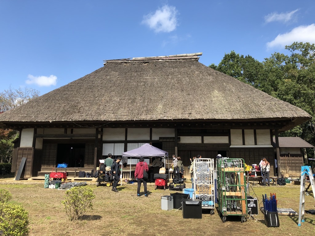 茅葺屋根の旧増田家住宅前の庭にスタッフの方や撮影機材が置かれ、撮影が行われている様子の写真