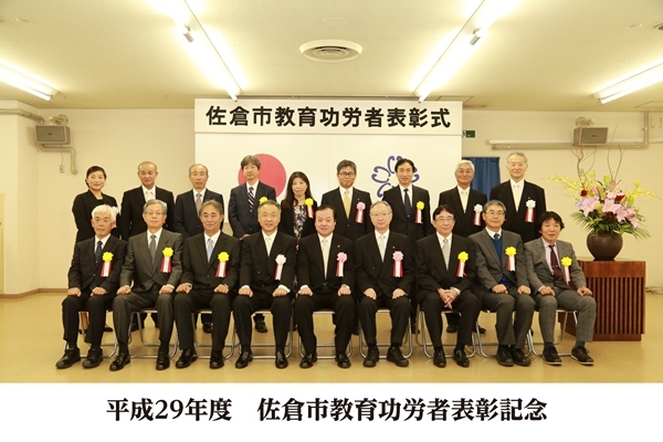 前列に9名、後列に9名の胸章リボンをつけた方々の集合写真