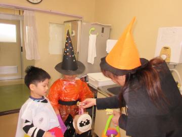 コスチュームを着た園児が、仮装した先生からお菓子をもらっている写真