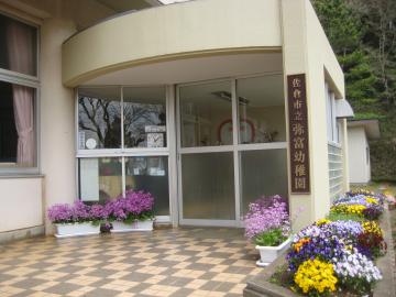 様々な花が植えられたプランターが並んでいる弥冨幼稚園の入口の写真