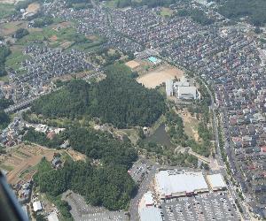 中央に緑の森が見え、その周りに集落がある染井野の住宅街の空撮写真