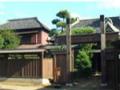 瓦屋根の立派な建物と蔵が植木に囲まれながら建っている様子の写真
