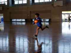 バスケットボールを抱えて体育館内を走っている女子生徒の写真