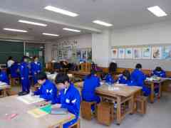 15名ほどの生徒が美術室で机に向かって絵を描いている写真
