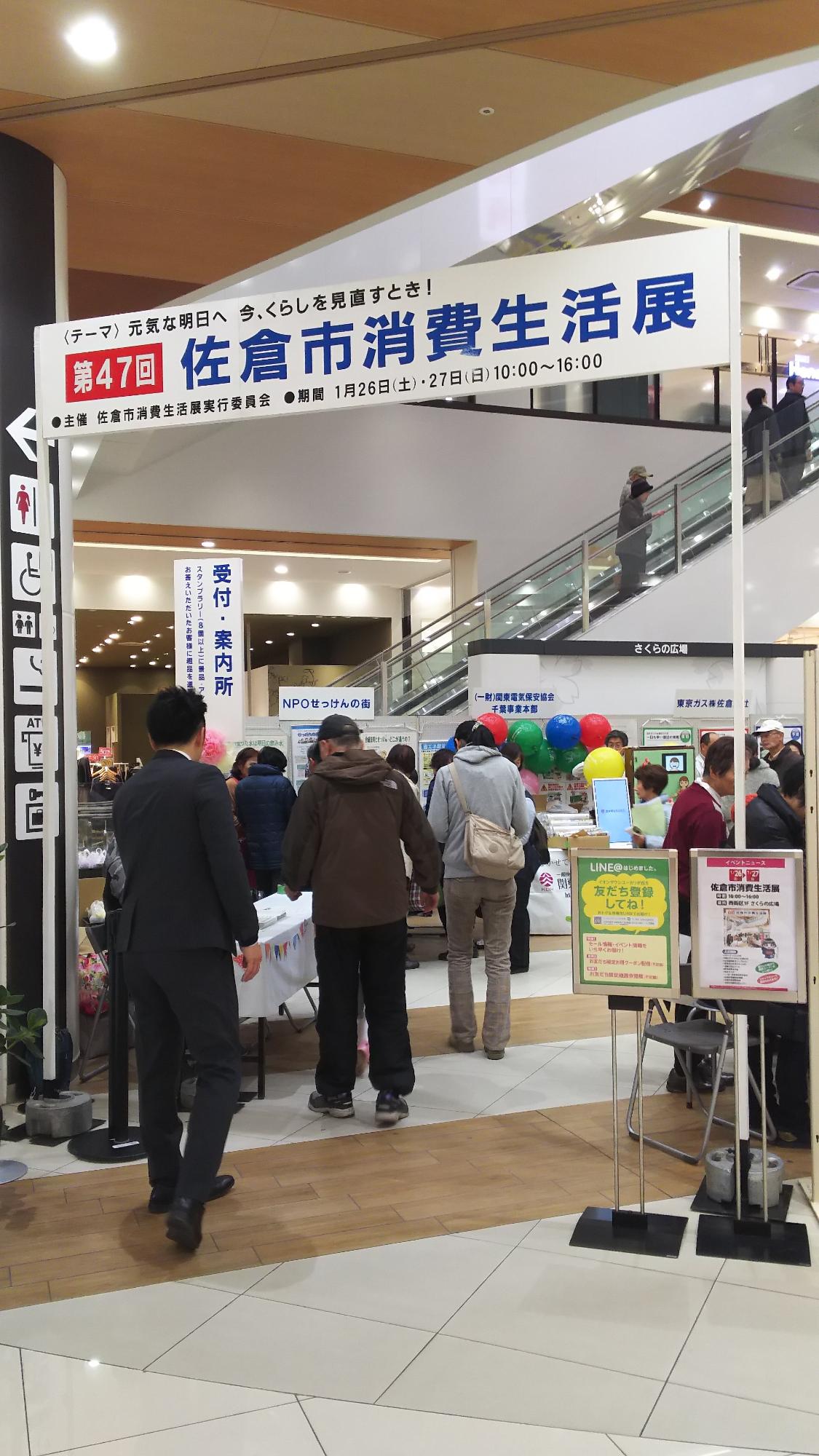 「第47回佐倉市消費生活展」と表示された会場、色々なパネルや品物が展示されており、沢山の来場者で賑わっている様子の写真