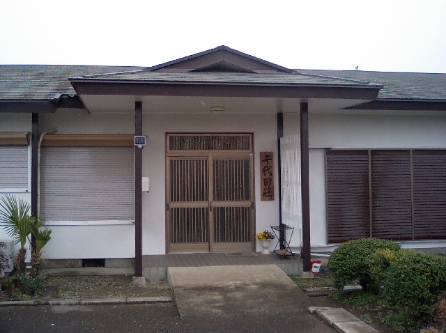 玄関横に「千代田荘」と書かれた表札がある外壁が白色の千代田荘の写真