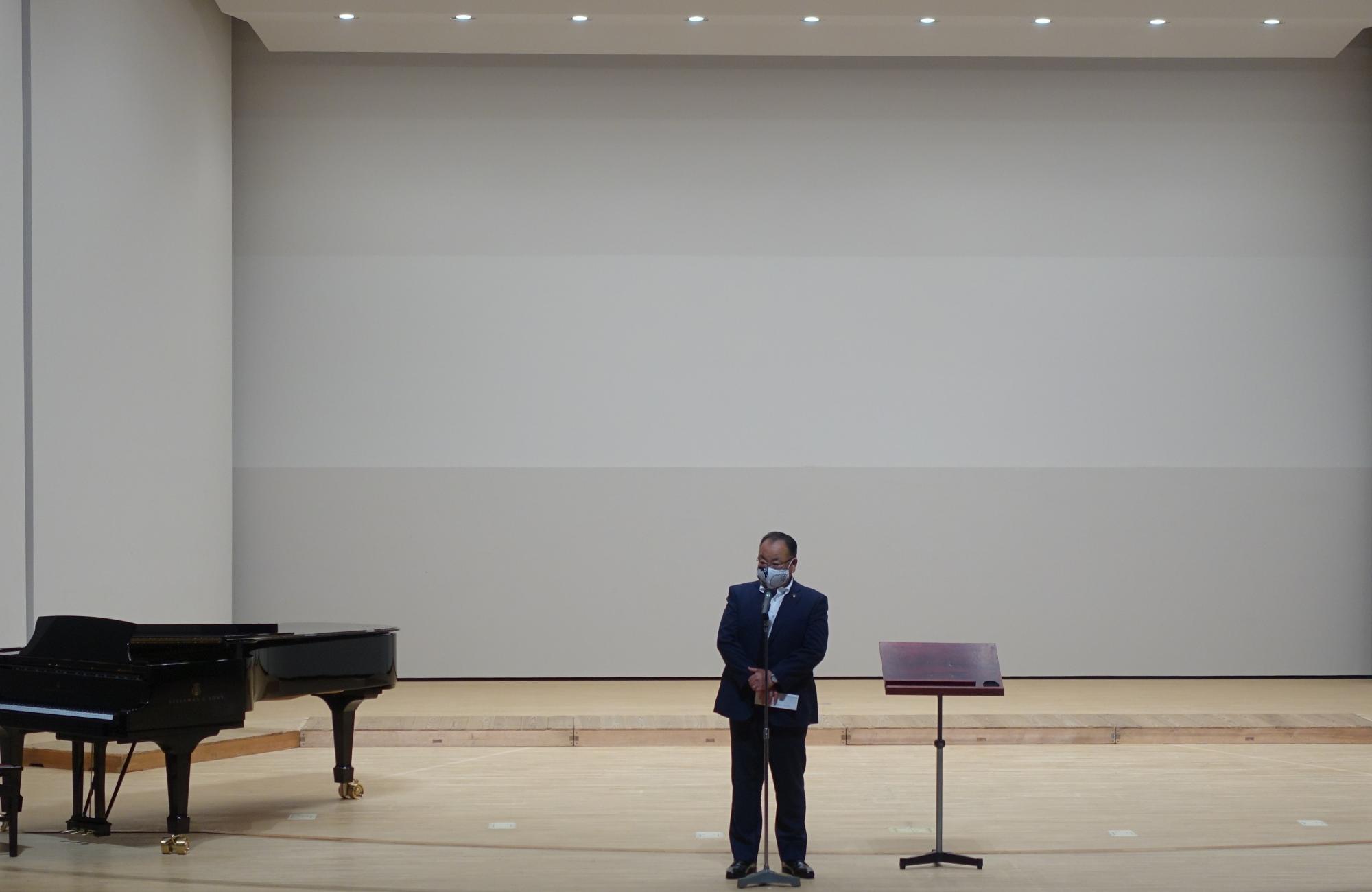 第45回さくら合唱のつどいで、グランドピアノが置かれた舞台の上で、マイクの前に立つ市長の写真
