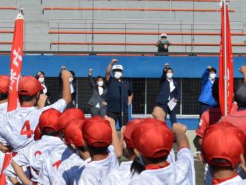 赤い帽子をかぶった少年野球のチームと、市長や関係者がこぶしを上にあげている写真