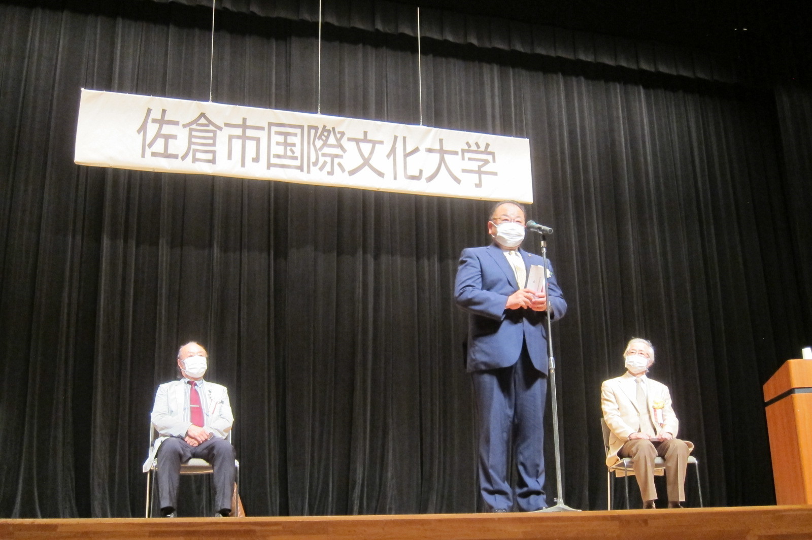 佐倉市国際文化大学 第2回公開講座にて、舞台上のマイクの前に立つ市長の写真