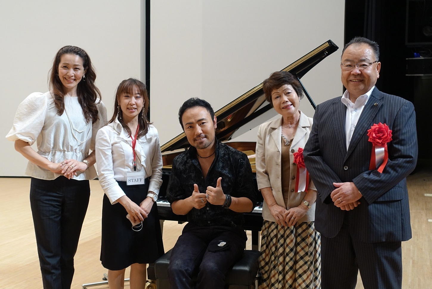 西川悟平トーク＆ピアノコンサートで、ピアノの前に並んでいる西川悟平さんや、関係者と市長が記念撮影をしている写真
