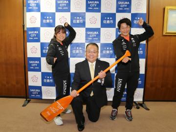 オレンジ色のパドルを持つ市長と、その横でポーズをとる吉岡和美選手と長洲百香選手の写真