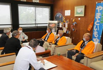 応接室にて、オレンジ色の法被を着た関係者や、市長が向かいあって座っている写真