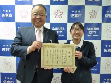 笑顔の市長と女子生徒が、一緒に賞状を持っている記念写真