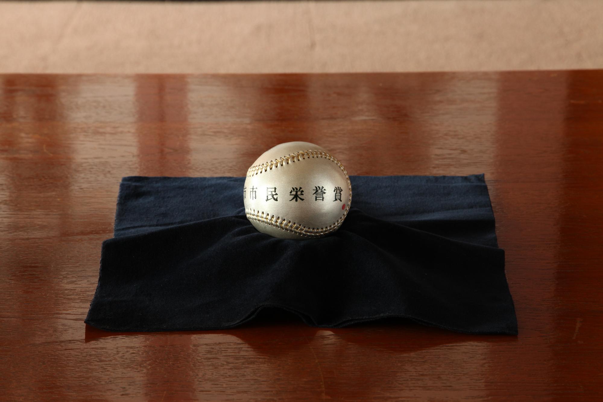 市民栄誉賞と書かれた銀色のボールが黒い布の上に置いてある写真