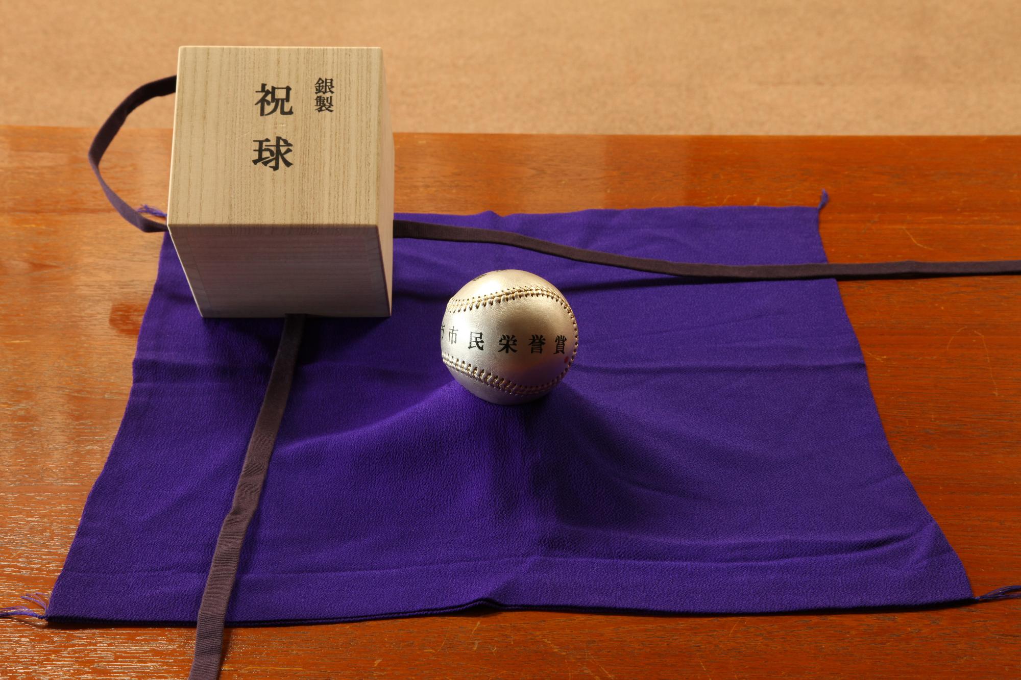 祝球と書かれた木箱と銀色のボールが、紫の布の上に置かれている写真