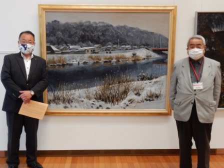 市長と男性が、額に入った絵画の両側に立っている写真