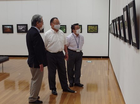 市長と男性2名が壁に掛けられた写真を見ている写真
