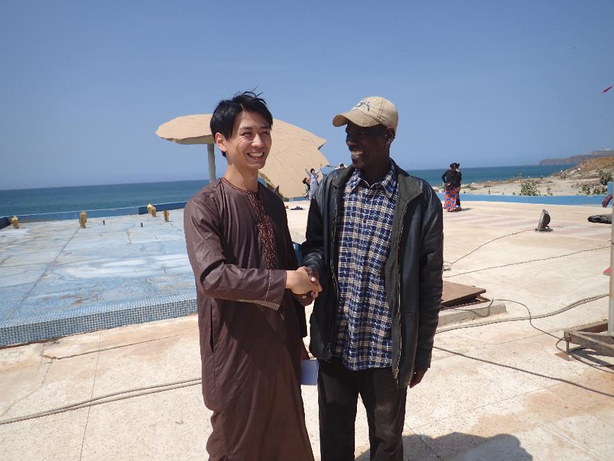 原田拓朗さんとキャップを被ったセネガルの男性が笑顔で握手をしている写真