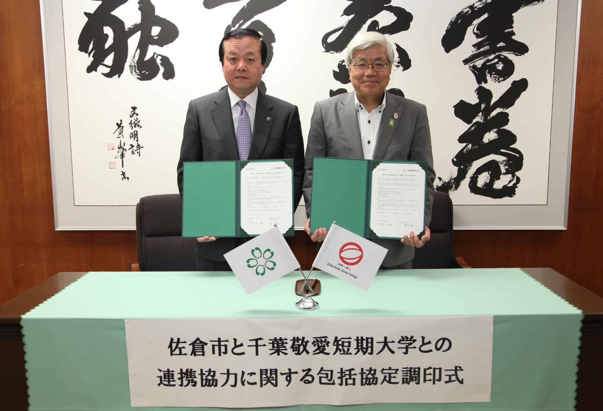 協定調停式にて蕨市長と千葉敬愛短期大学学長 明石さんがお互い協定書を手に持っている写真
