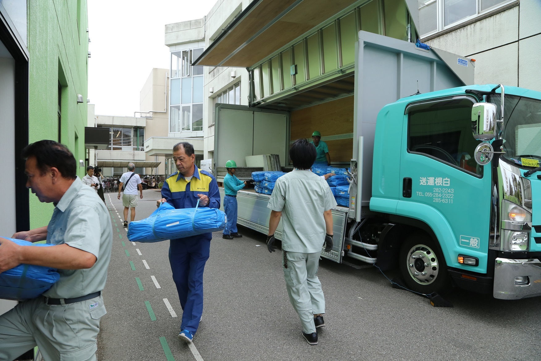 トラックの荷台からブルーシートを運び出している写真