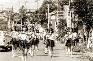 道路の半分を制服姿で交通安全パレードしている上志津小学校児童の白黒写真