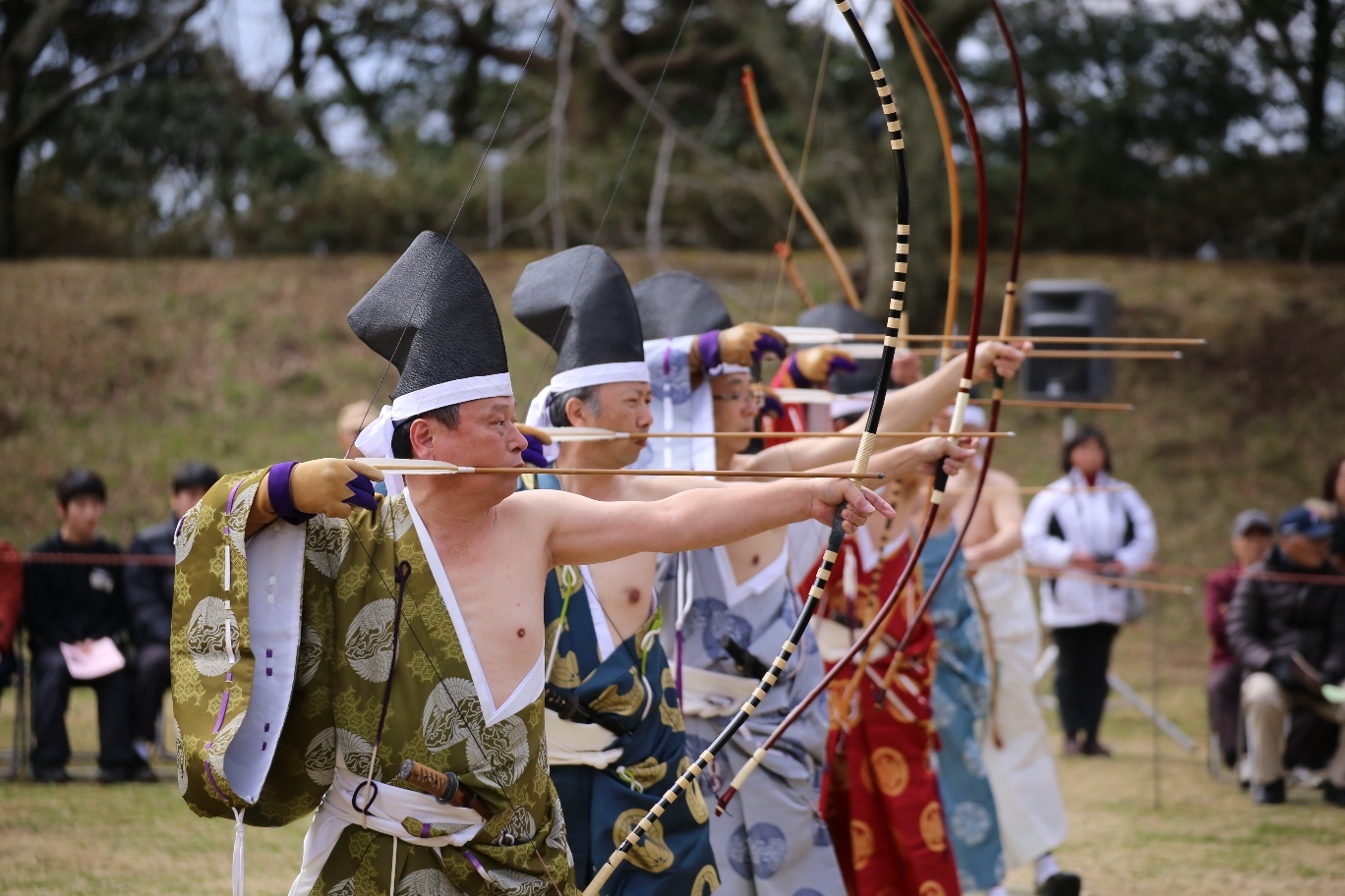 武士の格好をした男性たちが弓を構えて矢を引いている写真