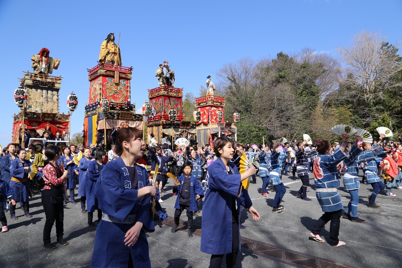 4台の山車の前で法被姿の人たちが踊りを披露している写真