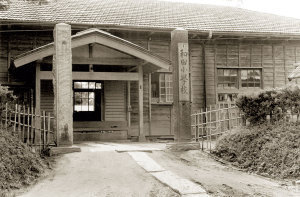和田小学校と書かれた門と奥の木造校舎入り口の白黒写真