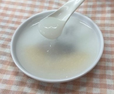 お皿に入っている10倍がゆのすりつぶしをスプーンですくっている写真