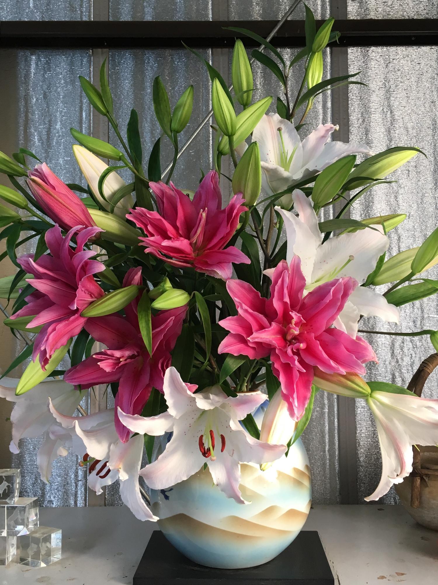 大きな花瓶に綺麗に飾られている白やピンクのユリの写真