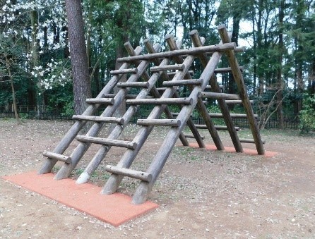 山型に丸太を組み、細い丸太で足場を施したアミダの山の遊具の写真
