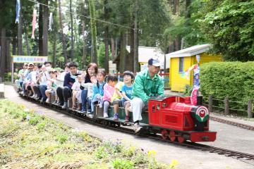 赤色の車体のミニ鉄道に大勢の親子が乗っている写真