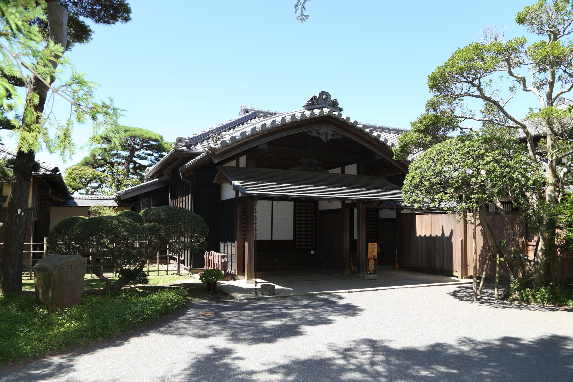 入り口にある石碑と木々の奥から建物が見えている旧堀田邸の写真