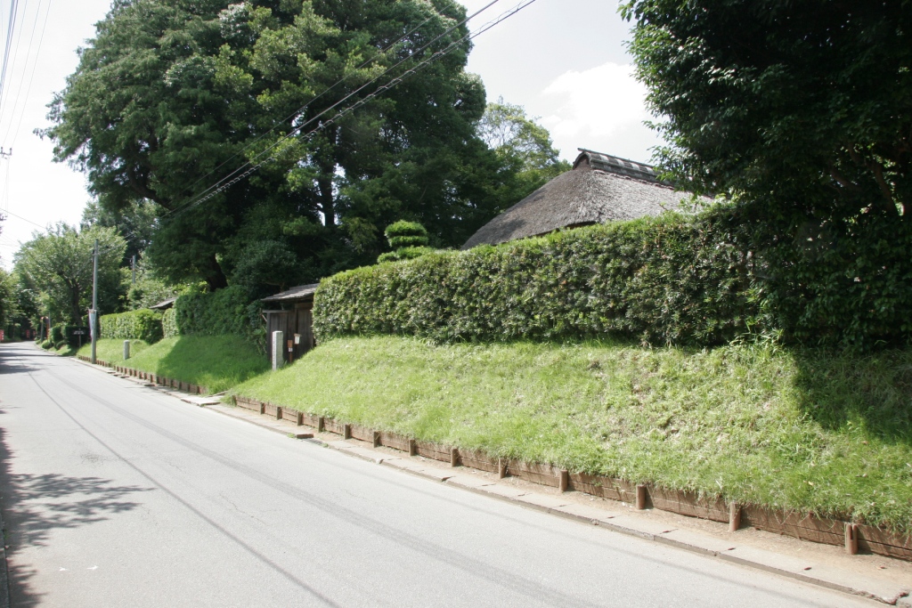 道路に面して築かれた土塁や生垣のある武家屋敷通りの写真