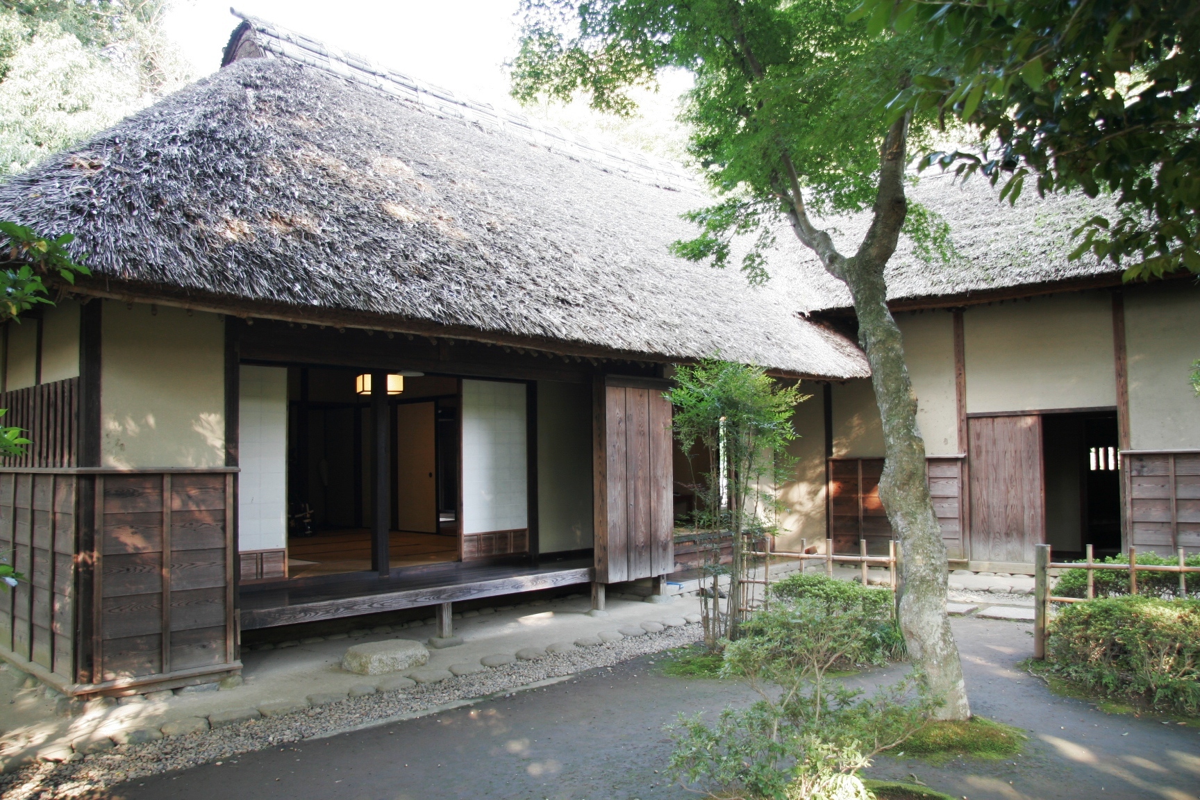 藁ぶき屋根ので縁側から和室が見える武家屋敷の写真