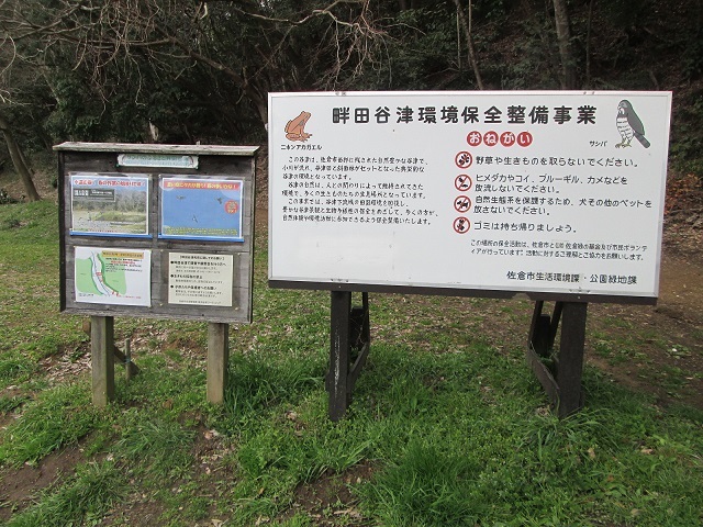 右側に畔田谷津環境保全整備事業について書かれた看板と左側に地図や写真など4枚の紙が貼られている案内板の写真