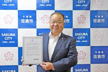 「佐倉市ゼロカーボンシティ宣言」の文を笑顔で持っている西田市長の写真