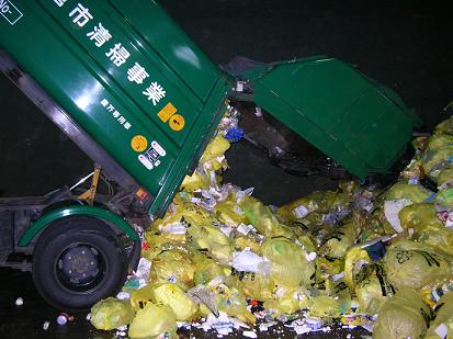 ごみ収集車で一時保管施設へ搬入された大量の黄色いごみ袋の写真