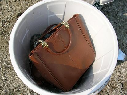 ゴミ箱の中の茶色い皮製のカバン（燃やせるごみ）の写真