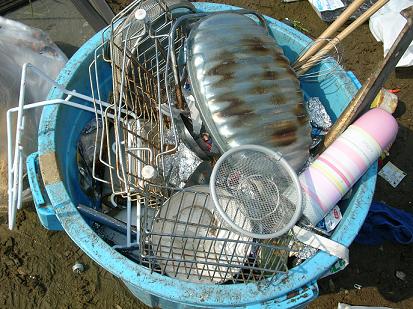 ゴミ箱の中の金属製の湯たんぽや水筒、調理器具（粗大ごみ雑芥類）の写真