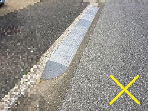 新しく乗り入れブロックが設置された道路脇に黄色でバツ印が書かれた写真